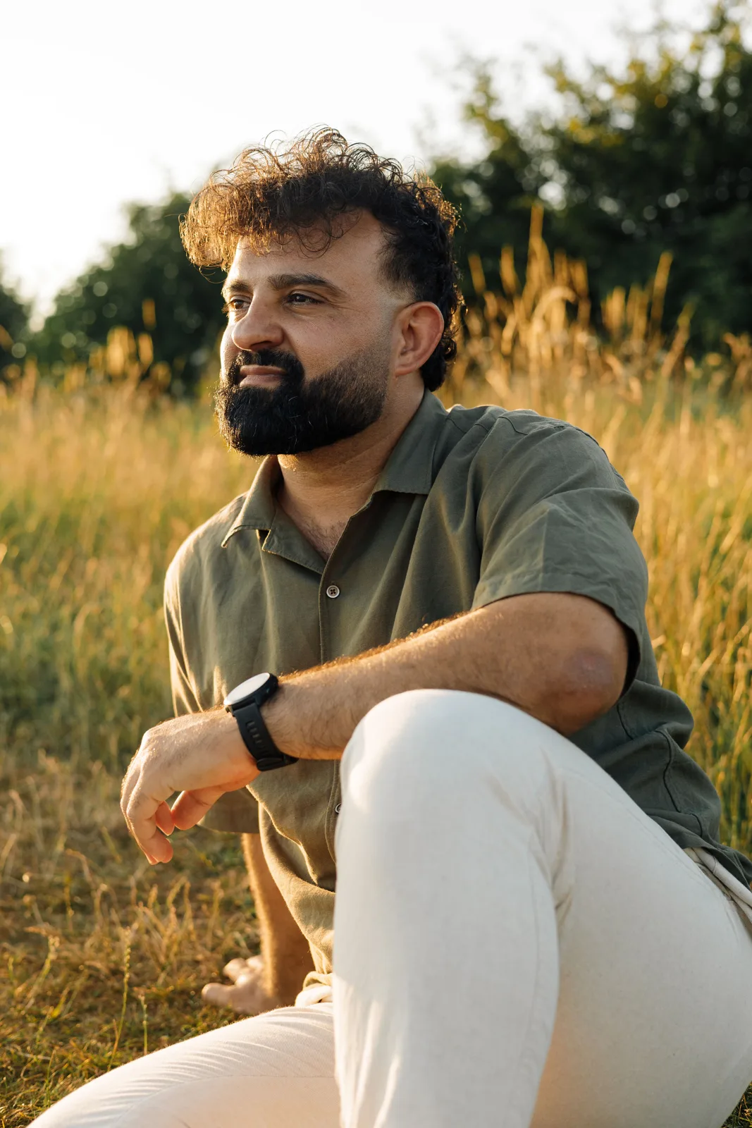 Amanj sitting in tall golden grass, looking into the distance