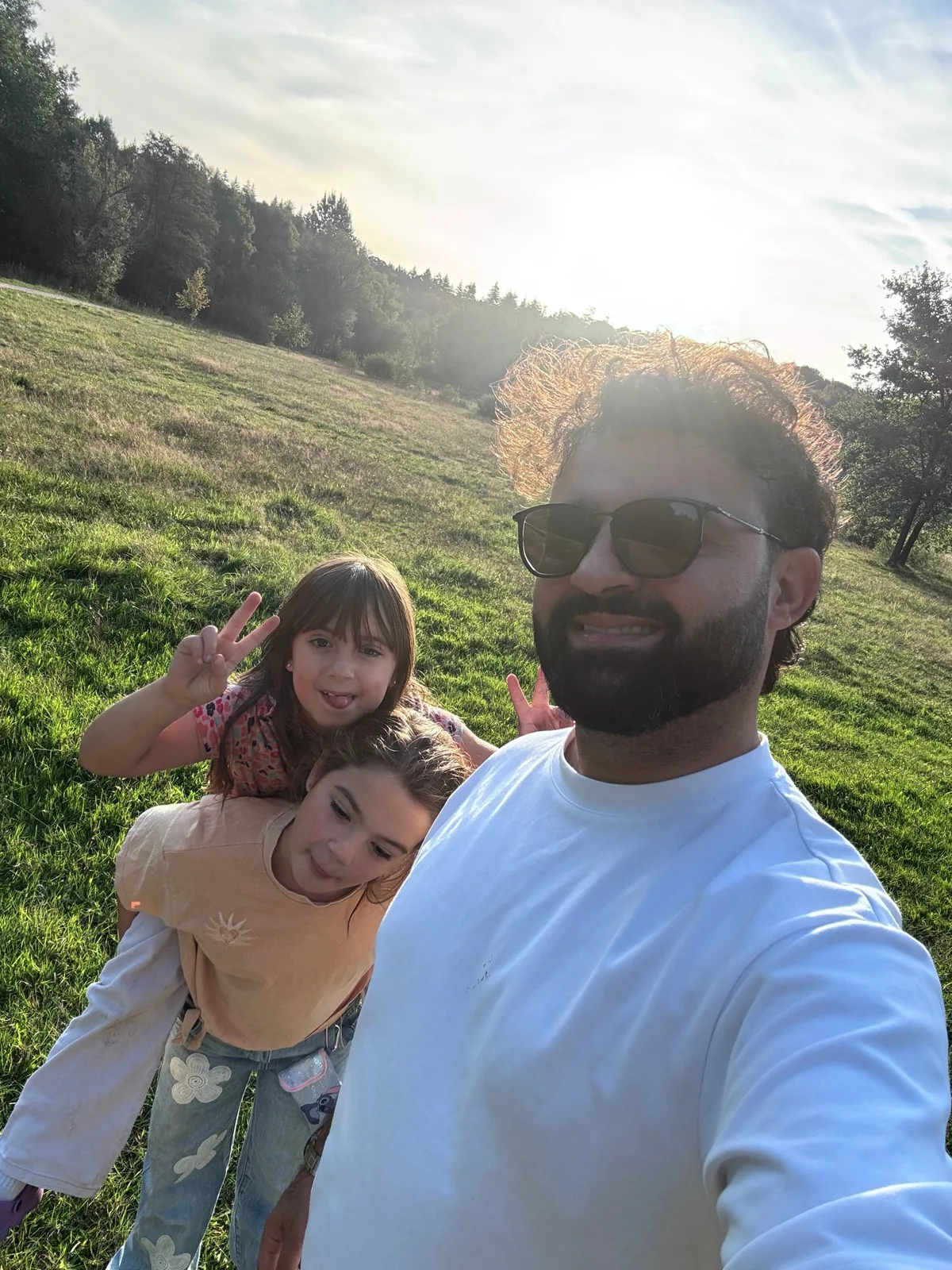 Amanj with his daughters in a sunny field